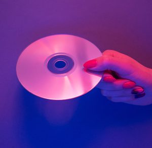 Woman hand holding CD disc in neon